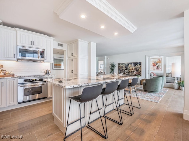 9375 Gulf Shore Dr Unit 601, Naples, FL 34108 - kitchen with stainless steel appliances, light wood finished floors, a kitchen bar, light stone counters, and open floor plan