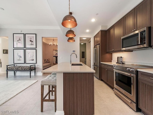 1030 3rd Ave S Unit 406, Naples, FL 34102 - kitchen featuring high quality appliances, a sink, dark brown cabinetry, a kitchen breakfast bar, and recessed lighting