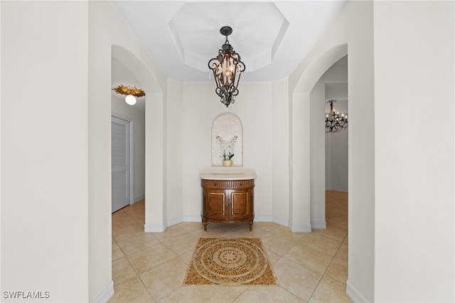 1630 Tarpon Bay Dr S Unit 102, Naples, FL 34119 - hall featuring arched walkways, a chandelier, light tile patterned flooring, and a raised ceiling