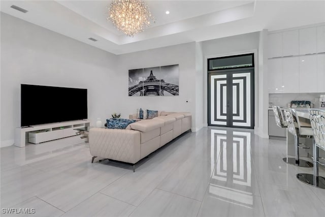 2909 2nd Ave NE, Naples, FL 34120 - living room featuring a chandelier, a tray ceiling, and baseboards