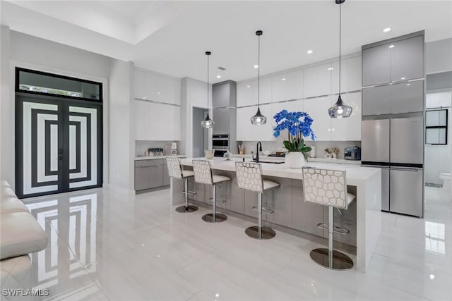 2909 2nd Ave NE, Naples, FL 34120 - kitchen featuring modern cabinets, freestanding refrigerator, gray cabinets, a breakfast bar area, and light countertops