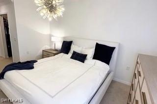 9834 Giaveno Cir Unit 1716, Naples, FL 34113 - bedroom with a chandelier, light colored carpet, and baseboards