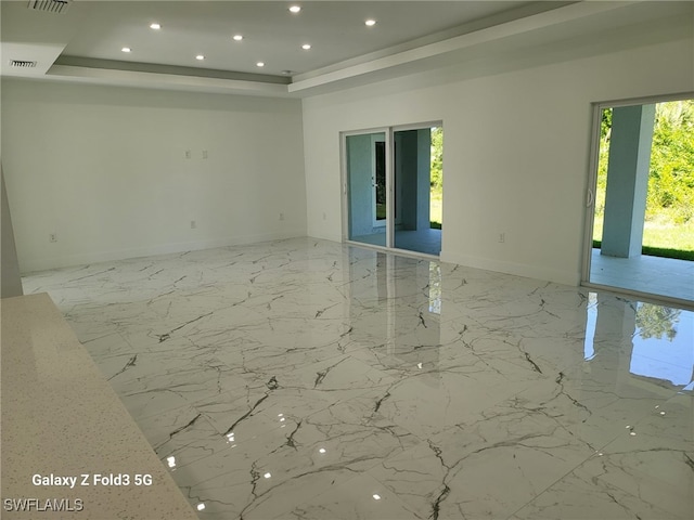 521 Frank Jewett Ave S, Lehigh Acres, FL 33974 - empty room with a tray ceiling, baseboards, recessed lighting, and light marble finish flooring