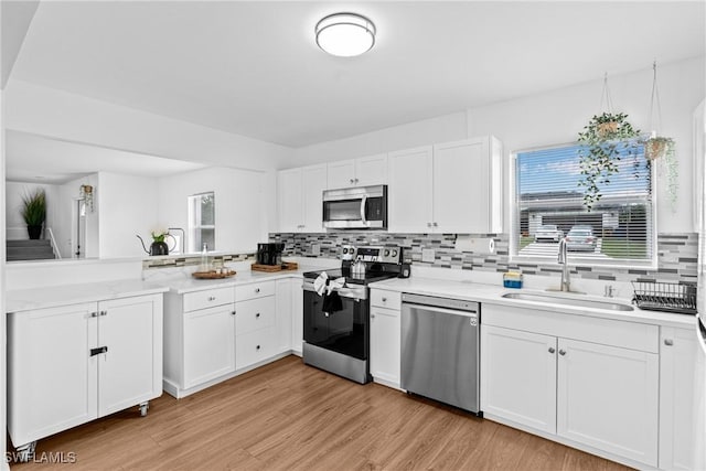 3303 6th St SW, Lehigh Acres, FL 33976 - kitchen featuring appliances with stainless steel finishes, a sink, tasteful backsplash, light wood-style flooring, and white cabinets