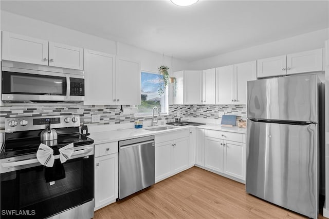3303 6th St SW, Lehigh Acres, FL 33976 - kitchen with appliances with stainless steel finishes, a sink, light countertops, white cabinetry, and light wood finished floors