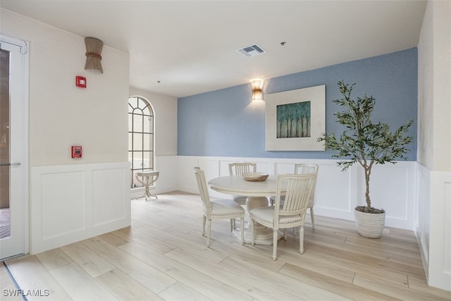 560 El Camino Real Unit 1304, Naples, FL 34119 - dining space with wainscoting, a decorative wall, and light wood-style flooring