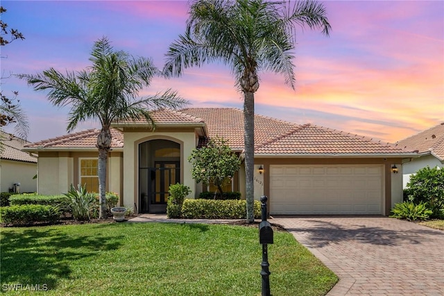 16121 Sand Ridge Ct, Fort Myers, FL 33908 - mediterranean / spanish-style home featuring stucco siding, an attached garage, decorative driveway, a tiled roof, and a lawn