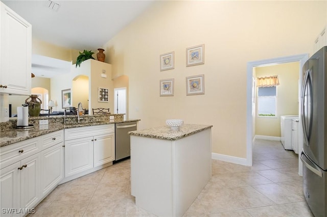 16121 Sand Ridge Ct, Fort Myers, FL 33908 - kitchen featuring appliances with stainless steel finishes, a sink, arched walkways, a high ceiling, and white cabinetry