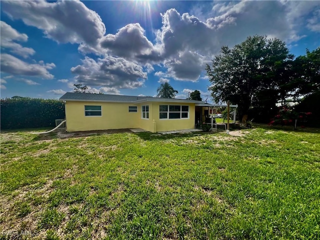 118 Alcala Ave, Lehigh Acres, FL 33936 - back of house featuring stucco siding and a yard
