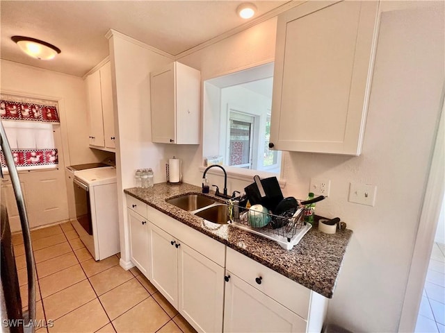 118 Alcala Ave, Lehigh Acres, FL 33936 - kitchen with light tile patterned flooring, washing machine and dryer, white cabinetry, a sink, and dark stone counters