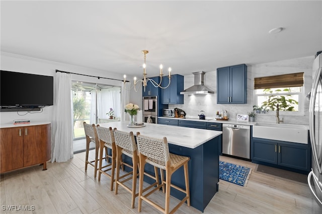 1549 Sandpiper St Unit 39, Naples, FL 34102 - kitchen with wall chimney exhaust hood, appliances with stainless steel finishes, blue cabinetry, a chandelier, and backsplash