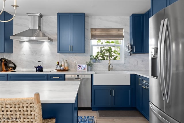 1549 Sandpiper St Unit 39, Naples, FL 34102 - kitchen featuring stainless steel appliances, wall chimney exhaust hood, blue cabinets, a sink, and tasteful backsplash