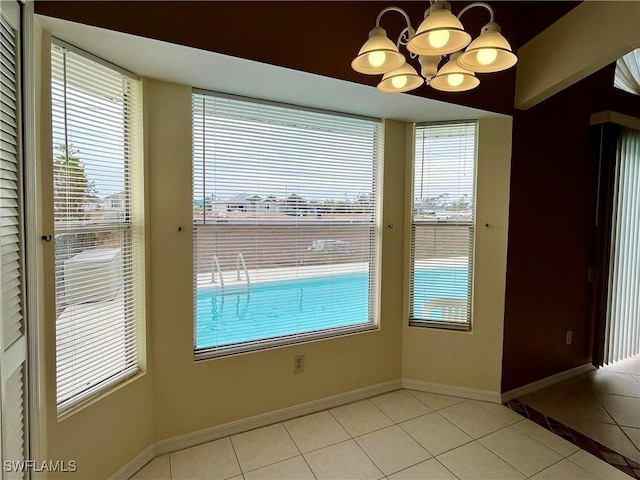 unfurnished dining area with light tile patterned floors, a chandelier, and baseboards