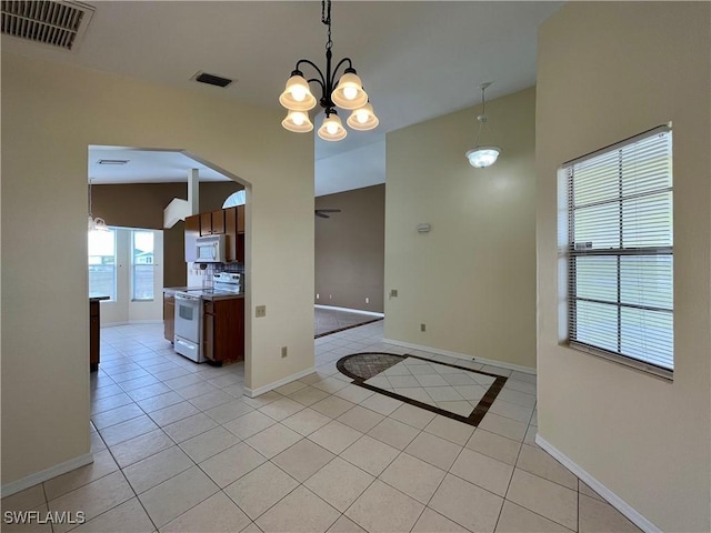 kitchen with white appliances, baseboards, light tile patterned floors, a chandelier, and arched walkways