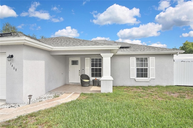 3408 26th St SW, Lehigh Acres, FL 33976 - property entrance featuring roof mounted solar panels, stucco siding, a yard, and roof with shingles