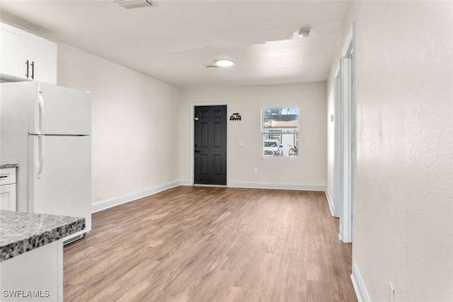 25/27 Cypress St, North Fort Myers, FL 33903 - kitchen featuring freestanding refrigerator, light wood-type flooring, white cabinets, baseboards, and light stone countertops