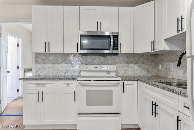 25/27 Cypress St, North Fort Myers, FL 33903 - kitchen with stainless steel microwave, white range with electric cooktop, white cabinets, and dark stone counters