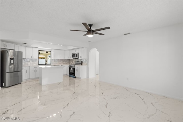 1306 SW 10th Pl, Cape Coral, FL 33991 - kitchen with appliances with stainless steel finishes, decorative backsplash, arched walkways, ceiling fan, and white cabinetry