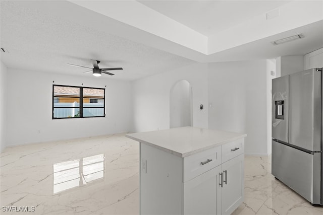 1306 SW 10th Pl, Cape Coral, FL 33991 - kitchen featuring stainless steel refrigerator with ice dispenser, light marble finish flooring, white cabinetry, arched walkways, and ceiling fan
