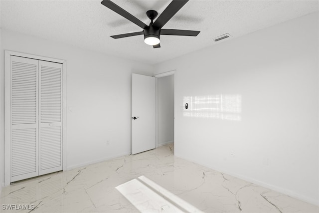 1306 SW 10th Pl, Cape Coral, FL 33991 - unfurnished bedroom with marble finish floors, a textured ceiling, a closet, a ceiling fan, and baseboards