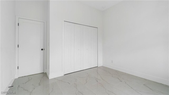 3315 Sunshine Blvd N, Lehigh Acres, FL 33971 - unfurnished bedroom with marble look tiles, baseboards, and a closet