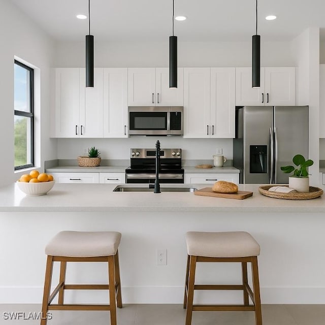 3315 Sunshine Blvd N, Lehigh Acres, FL 33971 - kitchen with appliances with stainless steel finishes, white cabinetry, a kitchen bar, recessed lighting, and light countertops