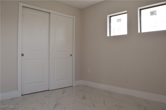 1013 Agnes Ave, Lehigh Acres, FL 33971 - unfurnished bedroom featuring marble look tile flooring, baseboards, and a closet