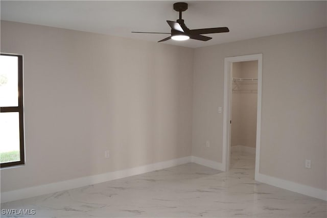1013 Agnes Ave, Lehigh Acres, FL 33971 - unfurnished bedroom with marble look tile flooring, baseboards, a spacious closet, a closet, and a ceiling fan