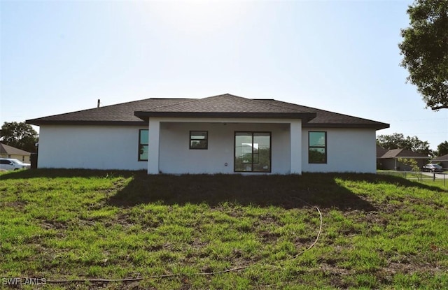 1013 Agnes Ave, Lehigh Acres, FL 33971 - rear view of house featuring stucco siding, a lawn, and a shingled roof