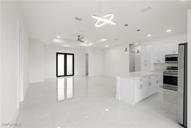 2811 27th St SW, Lehigh Acres, FL 33976 - kitchen featuring appliances with stainless steel finishes, a tray ceiling, open floor plan, white cabinets, and a center island