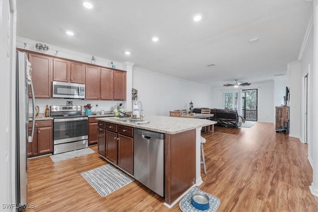 9052 Glenforest Dr, Naples, FL 34120 - kitchen featuring stainless steel appliances, crown molding, light wood-style floors, open floor plan, and a kitchen island with sink