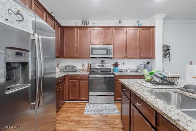 9052 Glenforest Dr, Naples, FL 34120 - kitchen with appliances with stainless steel finishes, ornamental molding, light wood-type flooring, and light stone countertops
