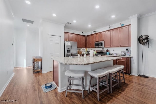 9052 Glenforest Dr, Naples, FL 34120 - kitchen featuring stainless steel appliances, wood finished floors, a kitchen breakfast bar, a kitchen island with sink, and ornamental molding