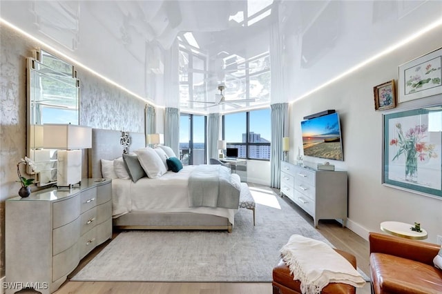 6001 Pelican Bay Blvd Unit 1405, Naples, FL 34108 - bedroom featuring a high ceiling, multiple windows, light wood-style floors, and baseboards