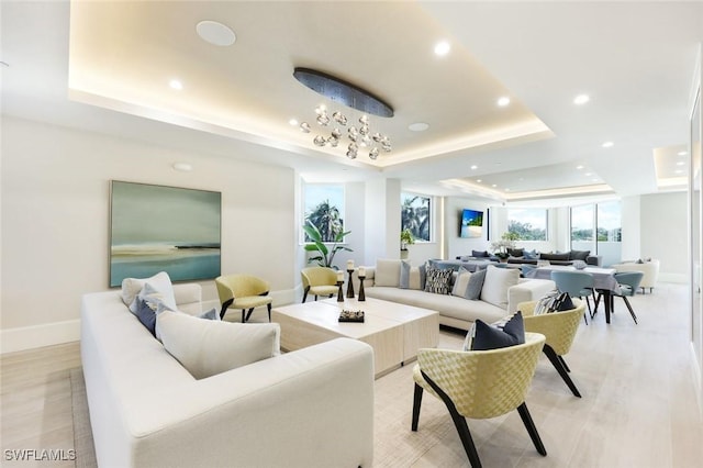 6001 Pelican Bay Blvd Unit 1405, Naples, FL 34108 - living room featuring a raised ceiling, baseboards, recessed lighting, light wood-style flooring, and a chandelier