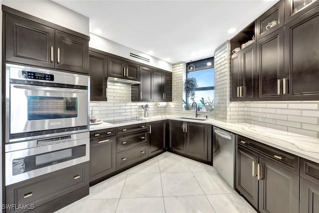 6001 Pelican Bay Blvd Unit 1405, Naples, FL 34108 - kitchen with stainless steel appliances, a sink, light tile patterned flooring, light stone counters, and decorative backsplash