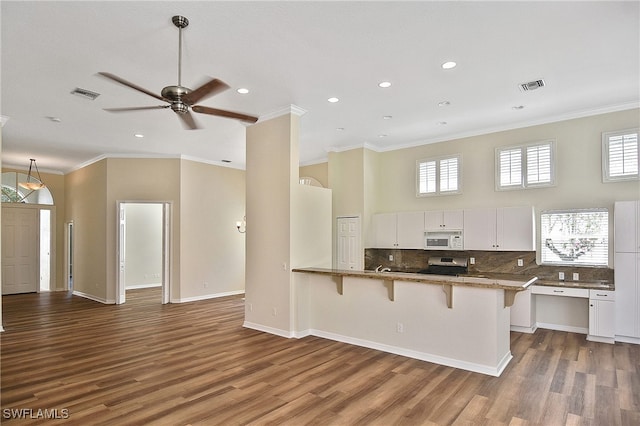 19741 Vintage Trace Cir, Estero, FL 33967 - kitchen with white microwave, ornamental molding, a breakfast bar, stainless steel range oven, and wood finished floors