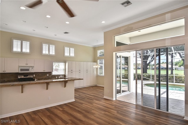 19741 Vintage Trace Cir, Estero, FL 33967 - kitchen with white microwave, ornamental molding, range, a breakfast bar area, and a towering ceiling