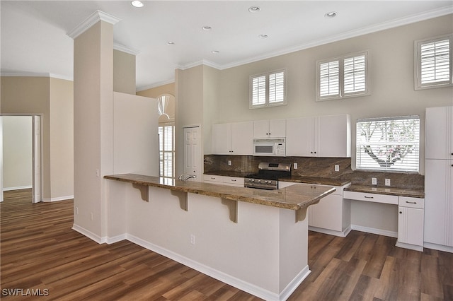 19741 Vintage Trace Cir, Estero, FL 33967 - kitchen featuring white microwave, stainless steel gas range oven, a breakfast bar area, a peninsula, and a towering ceiling