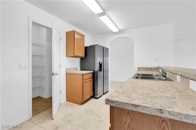 154 Shadowview Ct, Lehigh Acres, FL 33974 - kitchen featuring stainless steel fridge with ice dispenser, a sink, arched walkways, light countertops, and light tile patterned floors