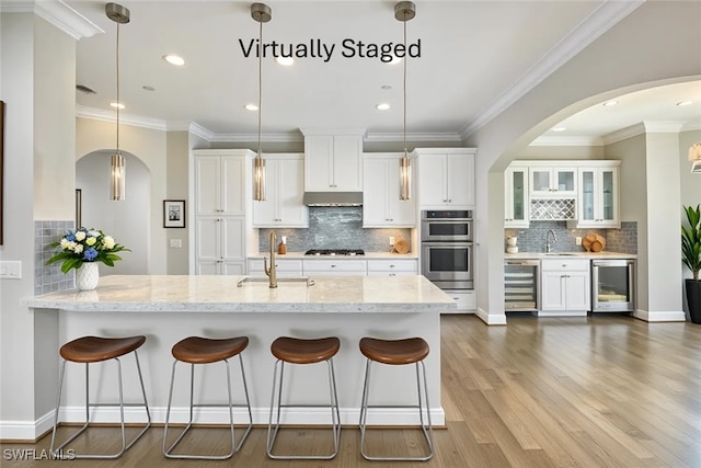 4771 Via Del Corso Ln Unit 302, Bonita Springs, FL 34134 - kitchen with beverage cooler, a sink, double oven, arched walkways, and recessed lighting