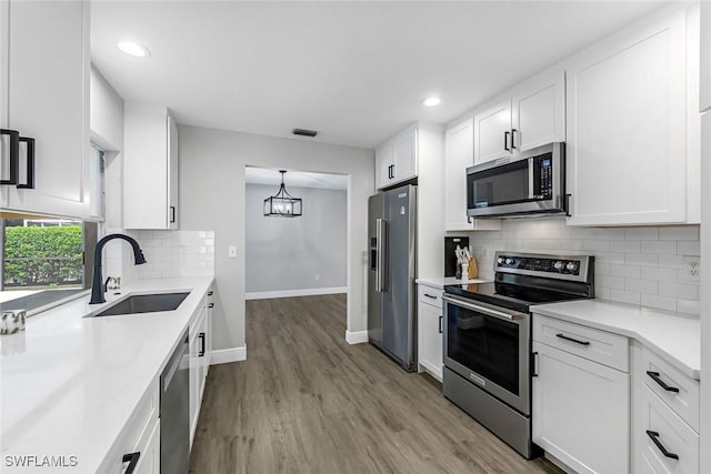 10268 Boca Cir, Naples, FL 34109 - kitchen with appliances with stainless steel finishes, a sink, light wood-type flooring, white cabinetry, and light countertops