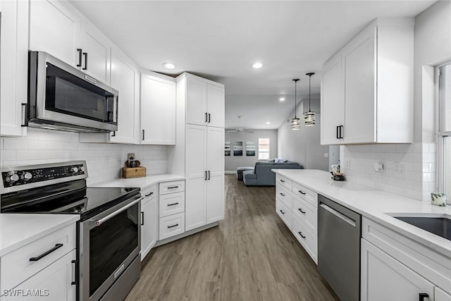 10268 Boca Cir, Naples, FL 34109 - kitchen featuring appliances with stainless steel finishes, light wood-style flooring, recessed lighting, white cabinetry, and light countertops