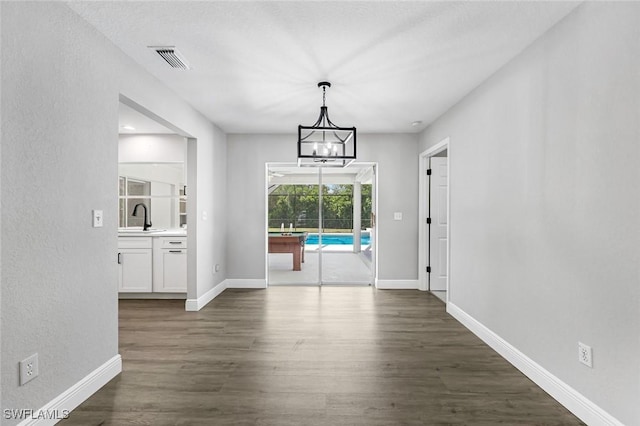 10268 Boca Cir, Naples, FL 34109 - unfurnished dining area with a sink, dark wood finished floors, a chandelier, and baseboards