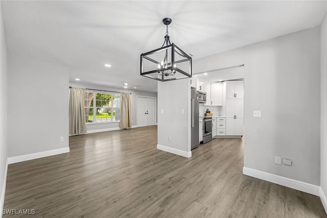 10268 Boca Cir, Naples, FL 34109 - unfurnished living room with a chandelier, baseboards, wood finished floors, and recessed lighting