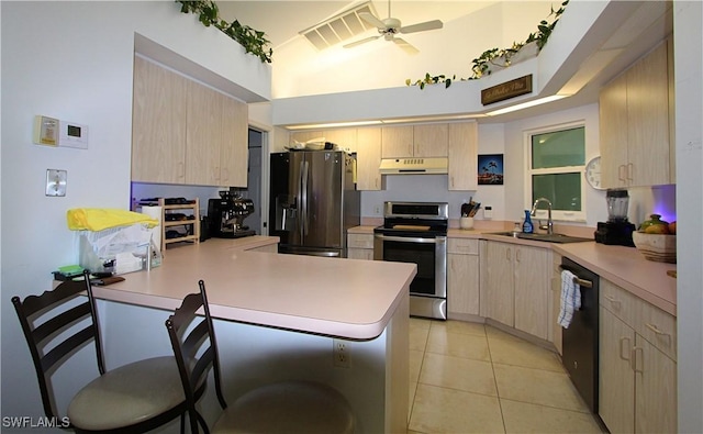 25561 Fairway Dunes Ct, Bonita Springs, FL 34135 - kitchen with appliances with stainless steel finishes, under cabinet range hood, light brown cabinetry, a peninsula, and light countertops