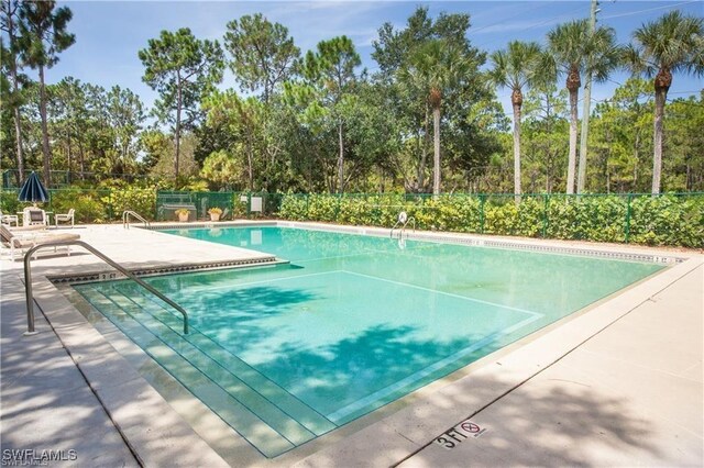 25561 Fairway Dunes Ct, Bonita Springs, FL 34135 - community pool featuring a patio and view of wooded area