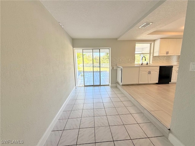 1438 Navigator Rd, Punta Gorda, FL 33983 - kitchen with black dishwasher, a textured ceiling, a textured wall, baseboards, and light countertops