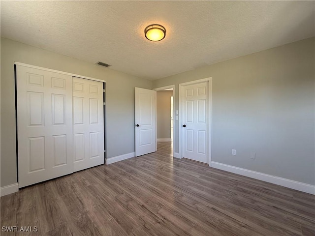 1438 Navigator Rd, Punta Gorda, FL 33983 - unfurnished bedroom with baseboards, dark wood-style flooring, a textured ceiling, and a closet