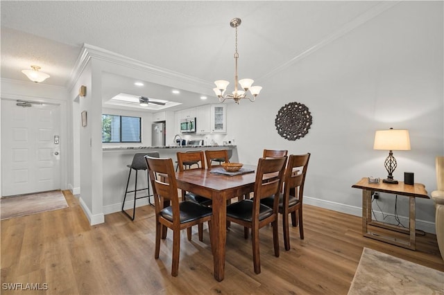 17451 Overhill Dr Unit F, Fort Myers, FL 33908 - dining area featuring ornamental molding, baseboards, wood finished floors, a chandelier, and a ceiling fan